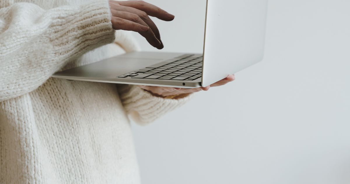 person holding laptop with minimal background.